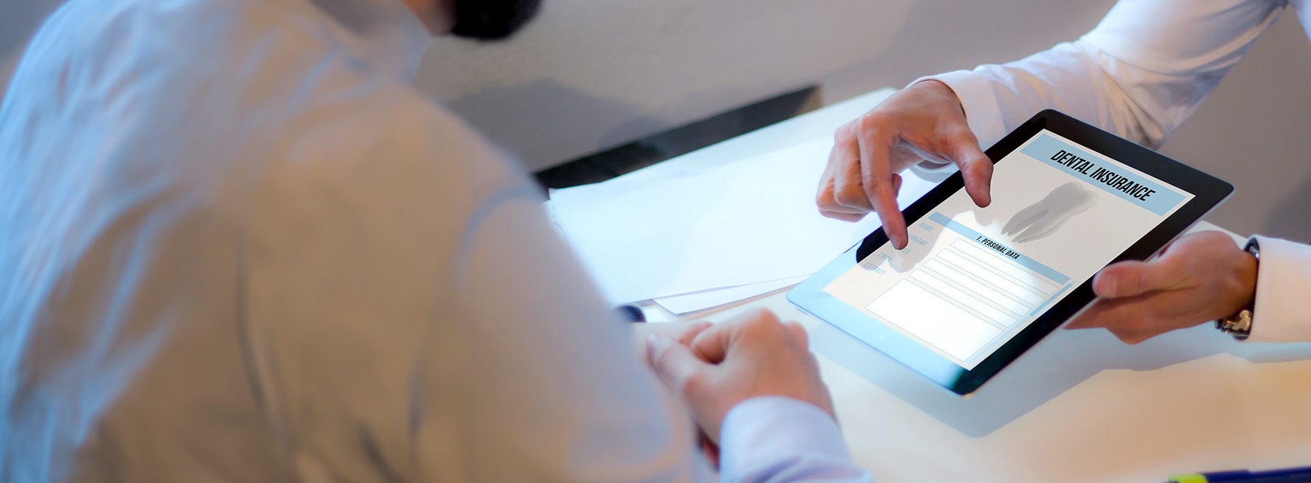 A person using a tablet computer with an interface displaying text, while another person looks on, both in a professional setting.