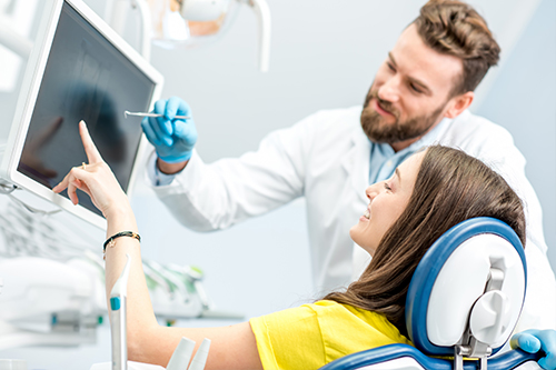 A man and woman in medical attire working with modern dental technology, likely in a dental office setting.