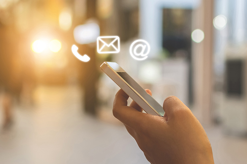 The image shows a person holding a smartphone with an email icon on the screen, suggesting communication activity.