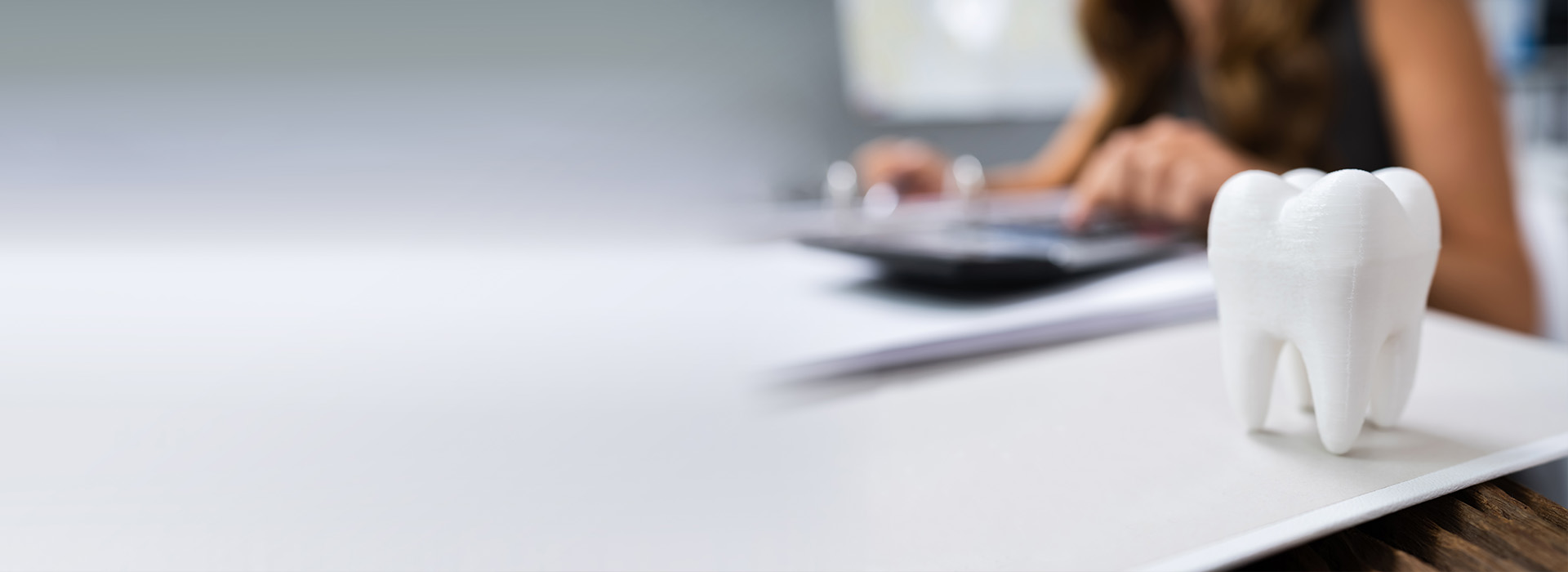 The image shows a person sitting at a desk with their back to the camera, working on a laptop, with a toothbrush placed on top of the laptop.