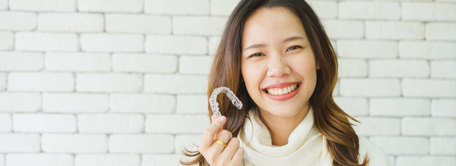 A woman holding a toothbrush with a smile on her face.