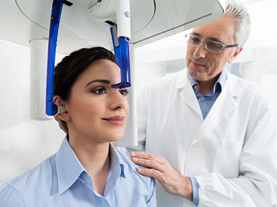 An image depicting a person seated in a dental chair with a dentist standing next to them, examining their teeth.