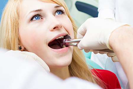 A woman receiving dental treatment in a professional setting, with a dentist performing the procedure.
