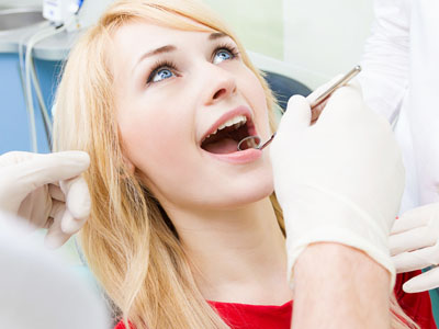 A woman receiving dental care with a focus on her open mouth and the dental instruments being used.